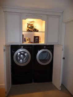 a washer and dryer in a small room with built - in shelving