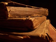 three old books are stacked on top of each other in this dark room with only one book left