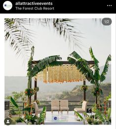 a table with chairs and flowers on it in front of an outdoor ceremony arch that is decorated with gold beads