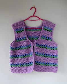 a crocheted vest hanging on a wall