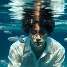 a man in white shirt under water with fish