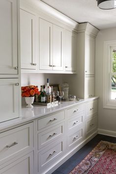 a kitchen filled with lots of white cupboards and counter top next to a window