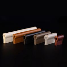 four different colored leather handles on a black surface