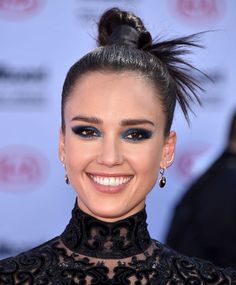 a close up of a person wearing black makeup and hair in a bun with blue eyeshadow