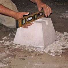 a man is using a pair of scissors to cut out concrete blocks in order to build a house