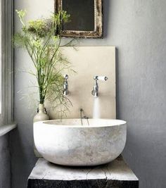 a white sink sitting under a mirror next to a window with plants in the bowl