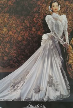 a woman in a white wedding dress standing next to a floral wall