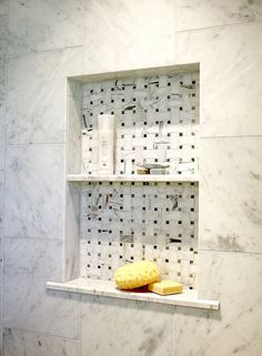 a bathroom with white marble walls and shelves