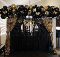 black and gold balloon arch with happy new year balloons on it in front of a window