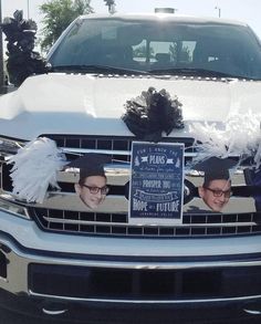 the front grille of a white truck decorated with black and white feathers, bows and decorations