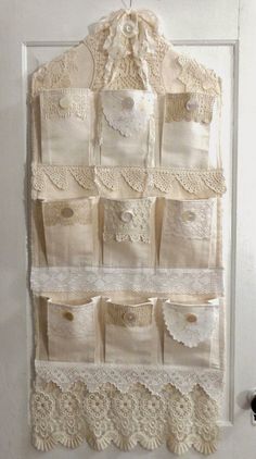 a white wall hanging with lots of doily on it's sides and pockets in the middle