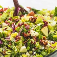 a salad with lettuce, red onions and other toppings in a glass bowl