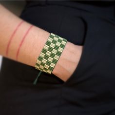 a person wearing a green and white checkered bracelet on their arm with red stripes