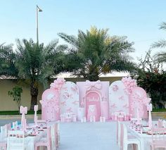 a pink and white wedding set up in the middle of a driveway with palm trees