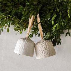 two white ceramic bells hanging from a tree