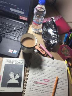 a laptop computer sitting on top of a wooden desk next to a cup of coffee