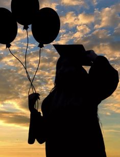 the silhouette of a person holding balloons in front of a cloudy sky at sunset or dawn