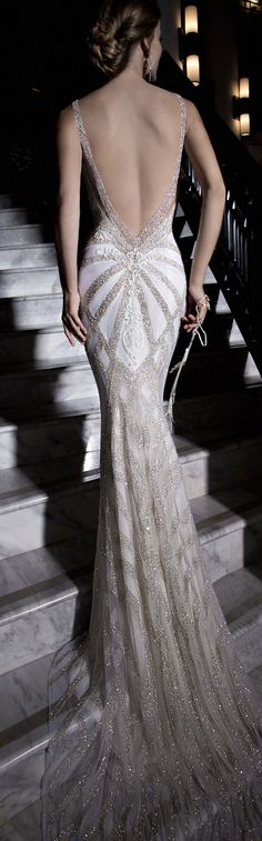 the back of a woman's wedding dress in front of stairs with lights on