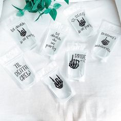 six plastic packets with black ink on them sitting next to a green plant and white t - shirt