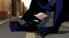 the animated batman is bending down on the sidewalk