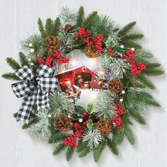 a christmas wreath with pine cones, evergreens and red berries is hung on the wall