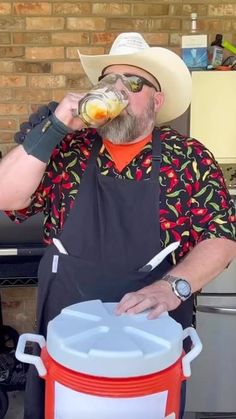 a man wearing an apron drinking from a bottle