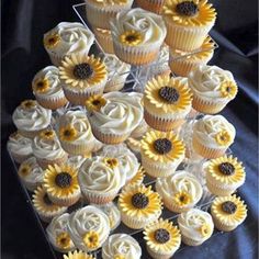 cupcakes with white frosting and sunflowers are arranged in the shape of a pyramid