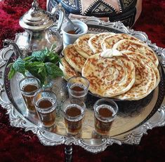 a tray with some food on top of it next to cups and saucers filled with drinks