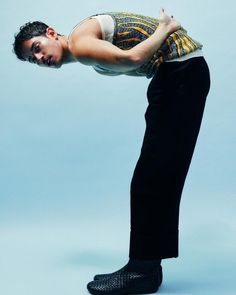 a man in black pants and white shirt is doing a handstand on a blue background