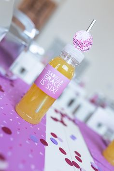 a small bottle filled with liquid sitting on top of a pink tablecloth covered table