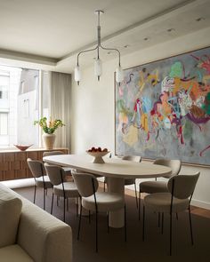 a dining room table and chairs in front of a large art piece on the wall