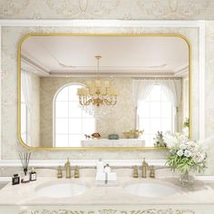 a bathroom with two sinks and a large mirror over it's sink, in front of a chandelier