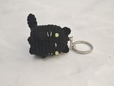 a black cat keychain is shown on a white surface