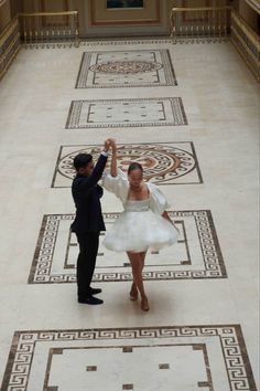 a bride and groom dancing in the middle of an ornate hallway with tile flooring