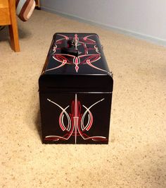 a black box with red designs on it sitting on the floor next to a chair