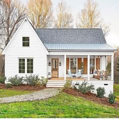 a small white house sitting on top of a lush green field