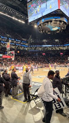 a group of people standing on top of a basketball court in front of a crowd