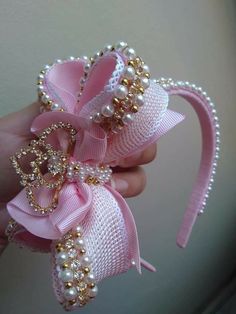 a hand holding a pink bow with pearls on it