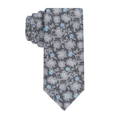 This Stafford Floral Tie in grey with blue accents blends sophistication with a touch of color, making it an excellent choice for formal and business settings. The grey background adorned with intricate floral patterns in lighter grey and blue provides a subtle yet striking look. Pair this tie with a crisp white shirt and a charcoal suit to enhance the blue accents, creating an elegant and balanced ensemble perfect for any professional gathering.Measurements: 15 Length/InchesBase Material: 100% Elegant Gray Business Tie, Elegant Patterned Tie With Floral Print, Elegant Gray Suit And Tie Accessories For Office, Charcoal Suit, Color Making, Crisp White Shirt, Grey Background, Blue Accents, Gray Background