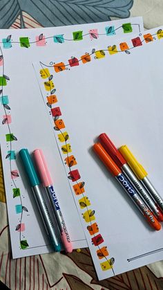 three pens are sitting on top of two sheets of paper with the same pattern and colors