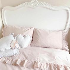 a bed with pink sheets and pillows on it