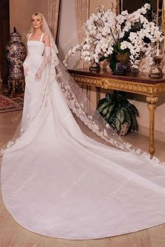 a woman in a white wedding dress standing next to a table with flowers on it