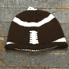 a brown and white knitted hat sitting on top of a wooden floor next to a brick wall