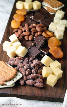 an assortment of nuts, crackers, and cheeses on a wooden platter