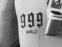 a person with a tattoo on their arm that says 999 world in black ink