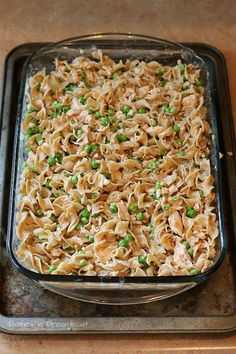 a casserole dish with peas and noodles in it on a baking sheet, ready to be eaten