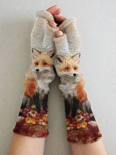 someone is holding their hands up to show the knitted gloves with an image of a fox on it