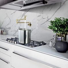 a stove top oven sitting next to a pot on top of a white countertop