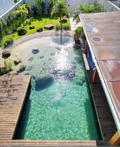 an outdoor swimming pool in the middle of a yard with wooden decking and water features