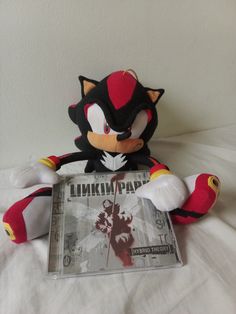 a stuffed animal that is next to a cd on a white sheet with the word linkin park printed on it